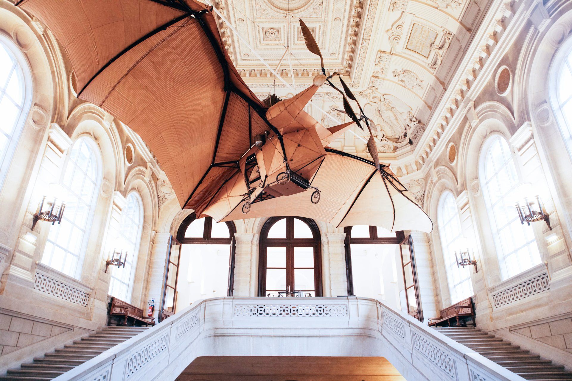 Blick in einen Museums-Raum mit einem hölzernen Fluggerät mit Flügeln an der Decke.