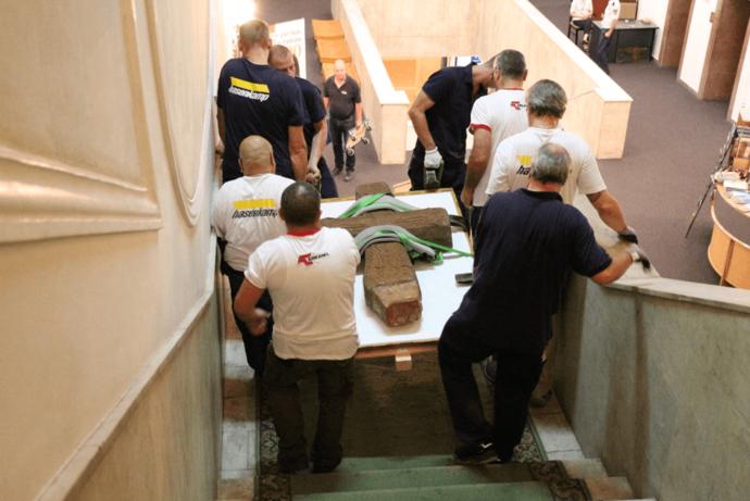 Mitarbeiter von hasenkamp tragen ein Kunstobjekt die Treppe herunter.